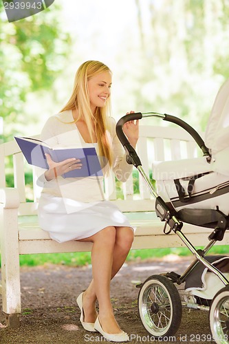 Image of happy mother with book and stroller in park