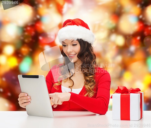 Image of smiling woman in santa hat with gift and tablet pc