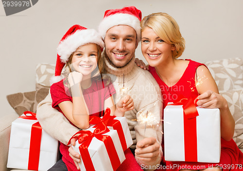 Image of smiling family holding gift boxes and sparkles