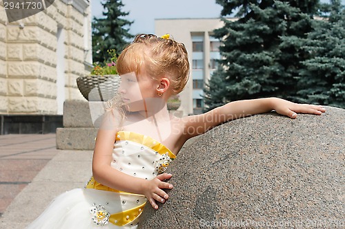 Image of Small girl near a marble ball in a summer day