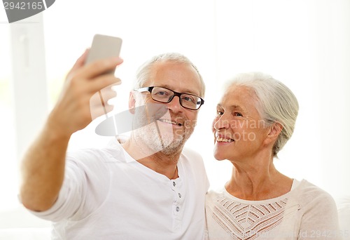 Image of happy senior couple with smartphone at home