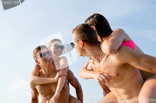 Image of smiling friends in sunglasses on summer beach