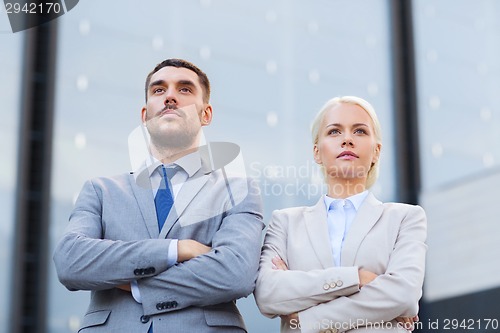 Image of serious businessmen standing over office building