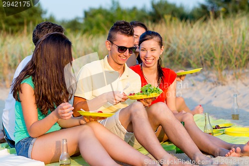 Image of smiling friends sitting on summer beach