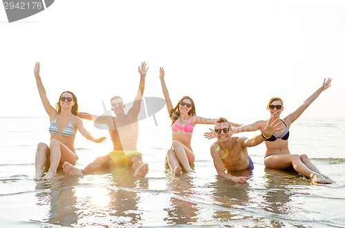 Image of smiling friends in sunglasses on summer beach