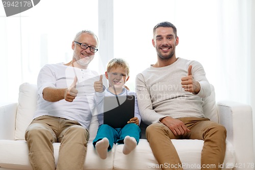 Image of smiling family with tablet pc at home