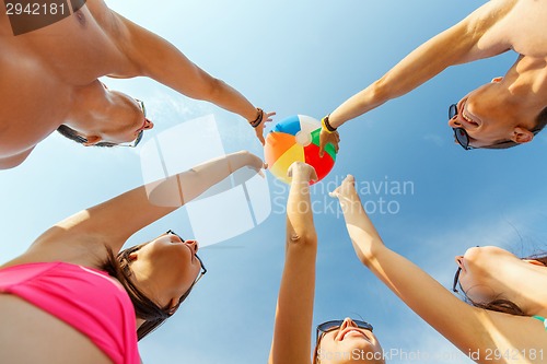 Image of smiling friends in circle on summer beach