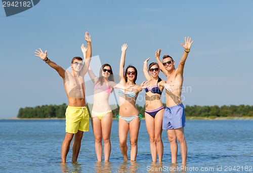 Image of smiling friends in sunglasses on summer beach