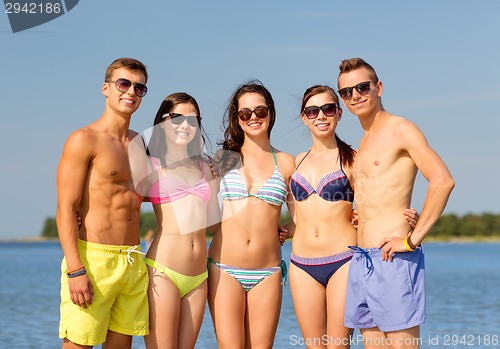 Image of smiling friends in sunglasses on summer beach