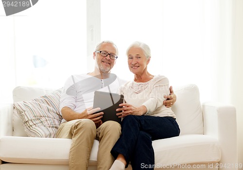 Image of happy senior couple with tablet pc at home