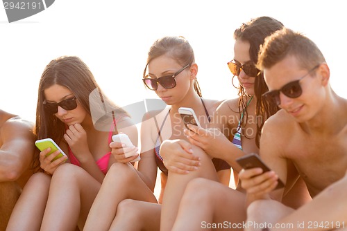 Image of friends with smartphones on beach