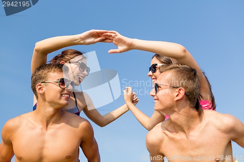 Image of smiling friends in sunglasses on summer beach