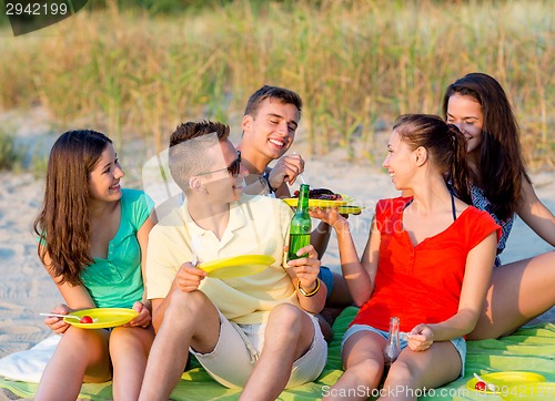 Image of smiling friends sitting on summer beach