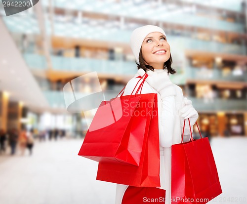 Image of smiling young woman with red shopping bags