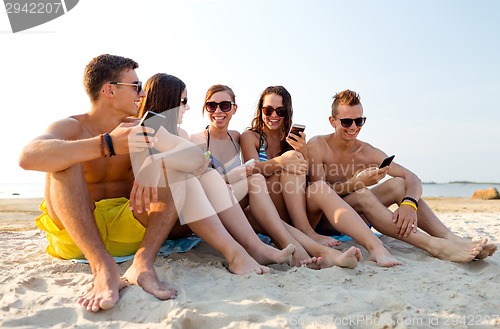 Image of friends with smartphones on beach