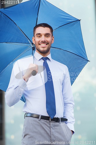 Image of young smiling businessman with umbrella outdoors