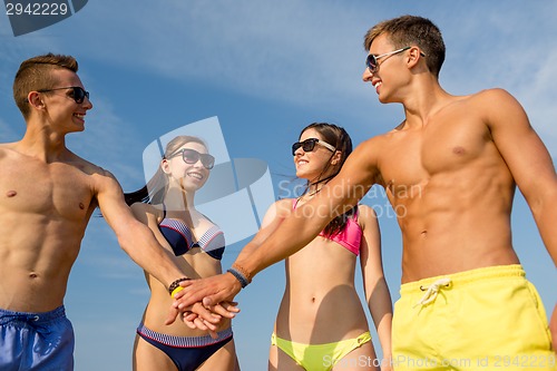 Image of smiling friends with hand on top outdoors