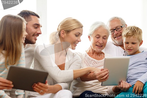 Image of smiling family with tablet pc at home