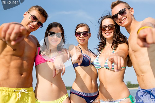 Image of smiling friends in sunglasses on summer beach