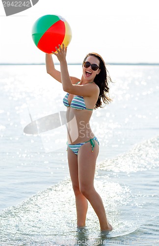 Image of smiling teenage girl sunglasses with ball on beach