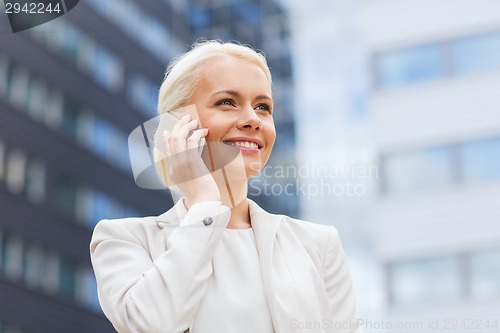 Image of smiling businesswoman with smartphone outdoors