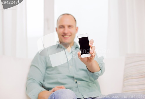 Image of close up of smiling man with smartphone at home