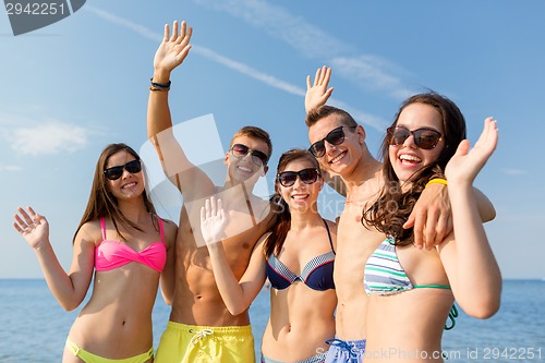 Image of smiling friends in sunglasses on summer beach