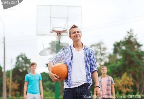 Image of group of smiling teenagers playing basketball