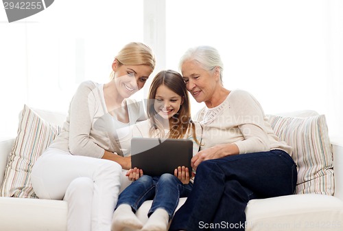 Image of smiling family with tablet pc at home