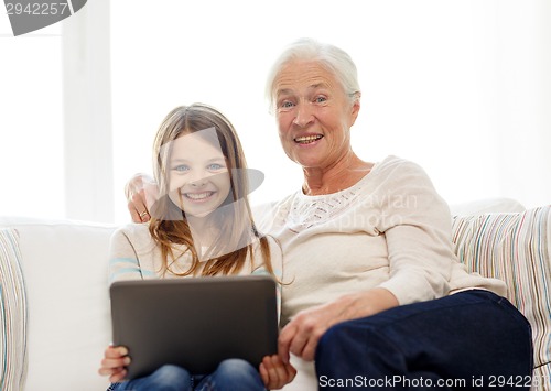 Image of smiling family with tablet pc at home