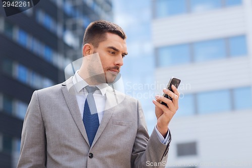 Image of serious businessman with smartphone outdoors