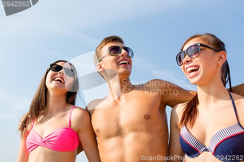 Image of smiling friends in sunglasses on summer beach