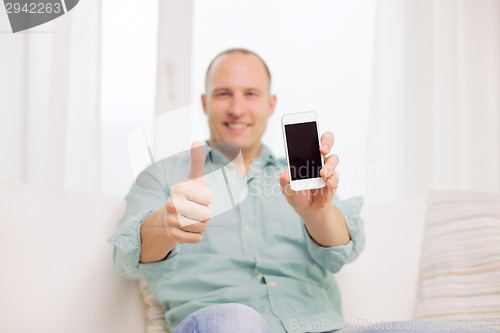 Image of close up of smiling man with smartphone at home