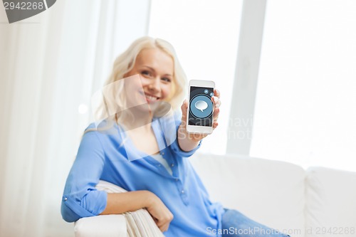 Image of smiling woman with smartphone at home