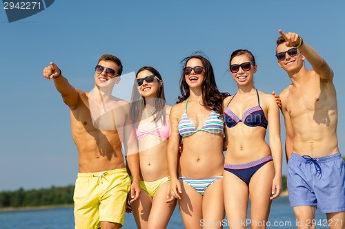 Image of smiling friends in sunglasses on summer beach