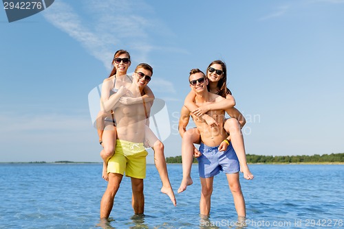 Image of smiling friends in sunglasses on summer beach