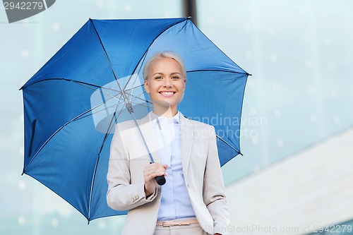 Image of young smiling businesswoman with umbrella outdoors