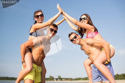 Image of smiling friends in sunglasses on summer beach