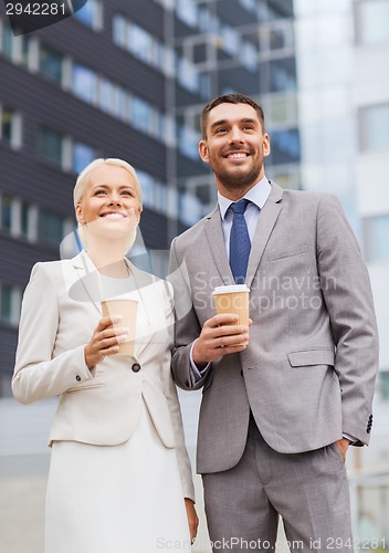 Image of smiling businessmen with paper cups outdoors