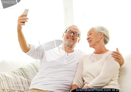 Image of happy senior couple with smartphone at home