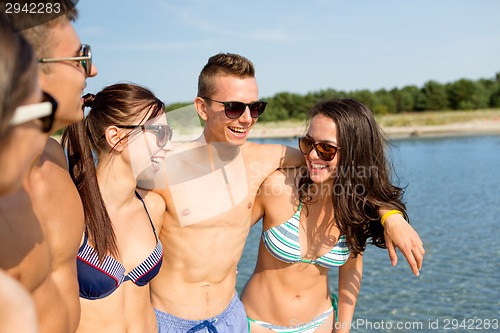 Image of smiling friends in sunglasses on summer beach