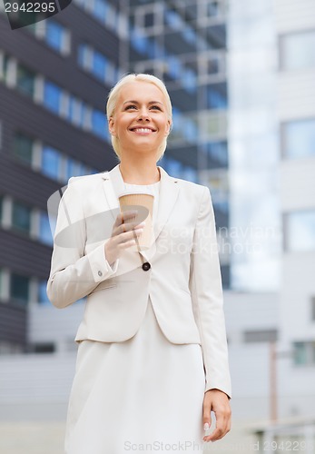 Image of smiling businesswoman with paper cup outdoors