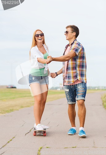 Image of smiling couple with skateboard outdoors