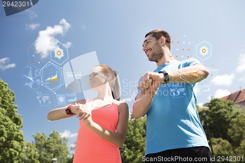 Image of smiling couple with heart rate watches outdoors