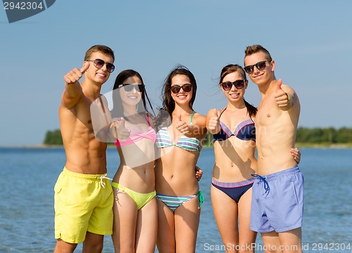 Image of smiling friends in sunglasses on summer beach