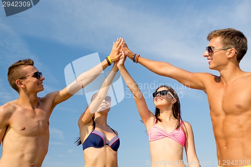 Image of smiling friends in sunglasses on summer beach