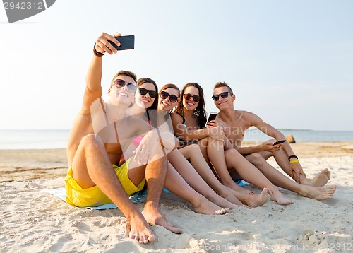 Image of friends with smartphones on beach