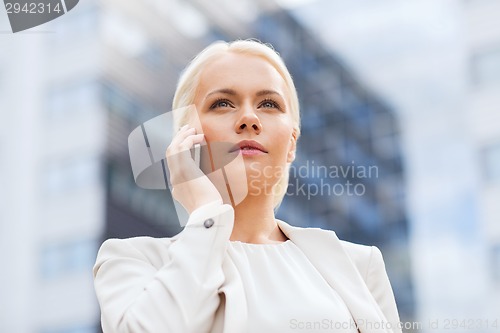 Image of serious businesswoman with smartphone outdoors