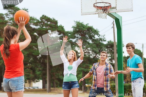 Image of group of smiling teenagers playing basketball