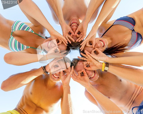 Image of smiling friends in circle on summer beach